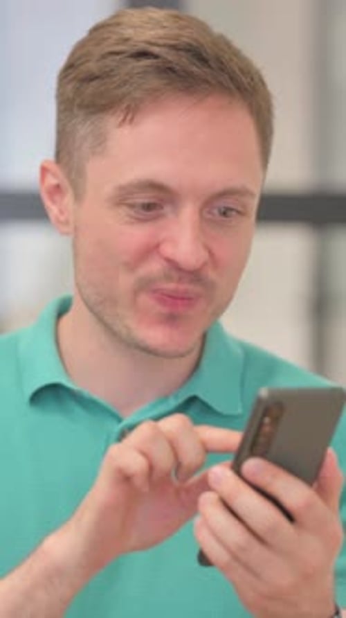 Smiling Man Using Mobile Phone Indoors