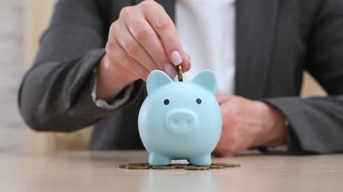 Businesswoman in Suit Putting Coins in Blue Piggy Bank Money Saving Concept