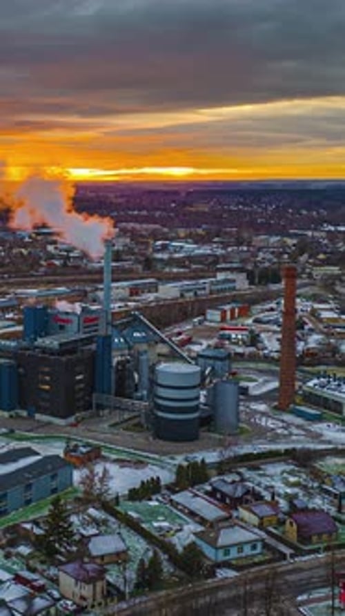 A Factory Emits Smoke Against a Snowy Cityscape at Sunset - Hyperlapse