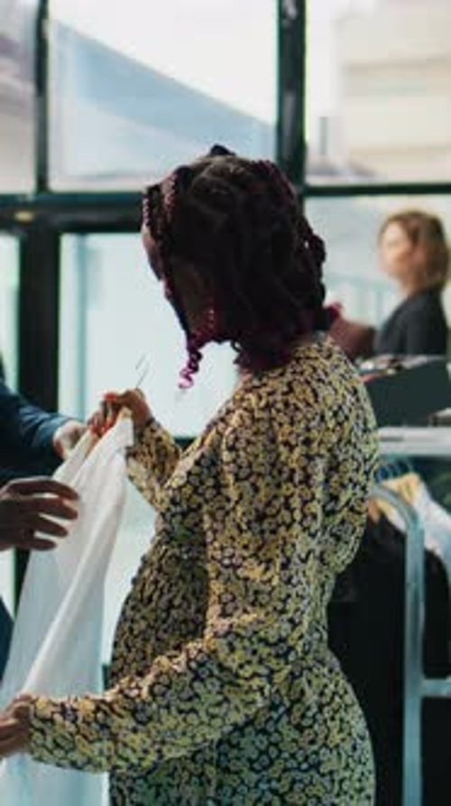 Man Helping Woman Choose Shirt in Store