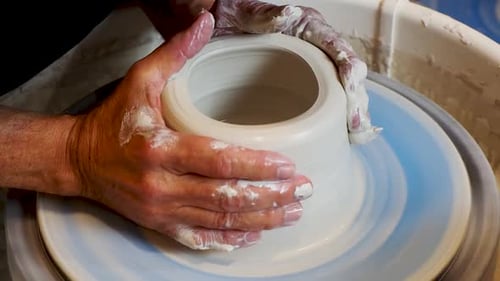 Close up of the potter's hand shaping and molding clay on a turning wheel .