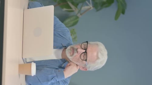 Tired Man with Gray Hair Works on Laptop