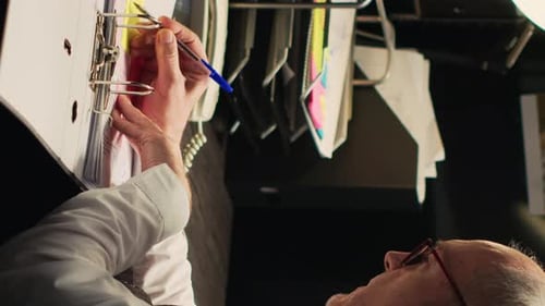 Man Writing in Binder at Workplace