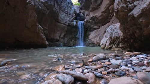 Waterfall flowing between rocky cliffs in peaceful natural landscape