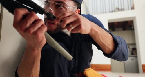 Man Smiling While Working on Pipe with Wrench