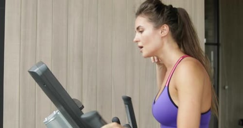 Sporty Woman on Elliptical Trainer in the Gym