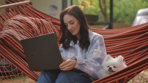 Woman Relaxing in Hammock With Dog and Laptop