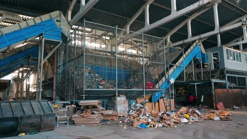 View of interior of a waste sorting plant. Garbage everywhere, special tools, workers