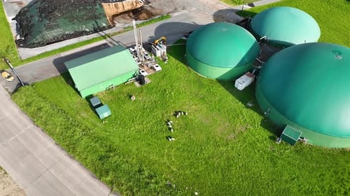 Aerial footage with camera tilt down to reveal green-roofed biogas digester facility, combined heat