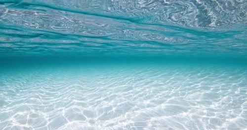 Transparenter klarer Ozean mit weißem sandigem Meeresboden, blauem Unterwasser-Hintergrund mit Wellen