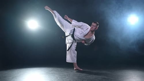 Starker Kämpfer im weißen Kimono für Karate-Kampfkünste mit schwarzem Gürtel bereitet sich auf den Kampf vor
