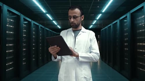 Technology Officer at Big Data Center uses a tablet computer, technician in scrubs