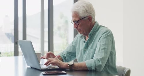 Senior Man Typing on Laptop at Home
