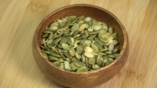 Peeled Pumpkin Seeds Pile Rotating in a Wooden Bowl. Healthy Vegetarian Vegan Raw Food