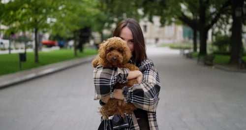 Woman Holds Poodle Dog in City Park