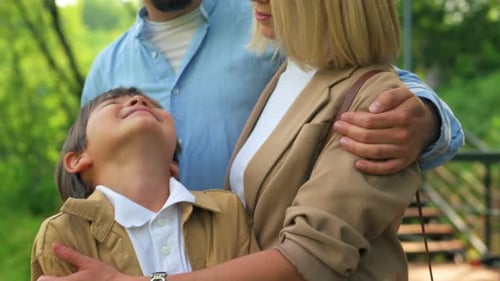 Happy Young Family Hugging Together in a Park Clip