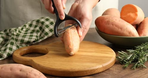 Hands Peeling Sweet Potato on Wooden Cutting Board