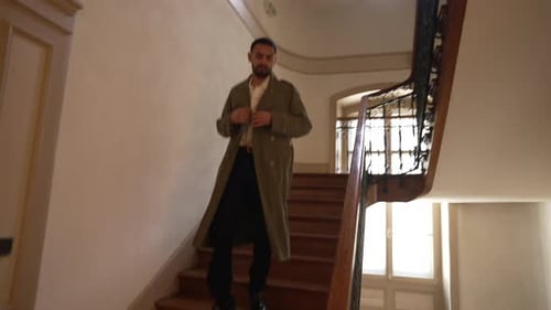 One Middle Eastern man wearing jacket leaving building. Person stepping down wooden stairs.