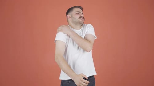 Man Rubs Shoulder in Discomfort
