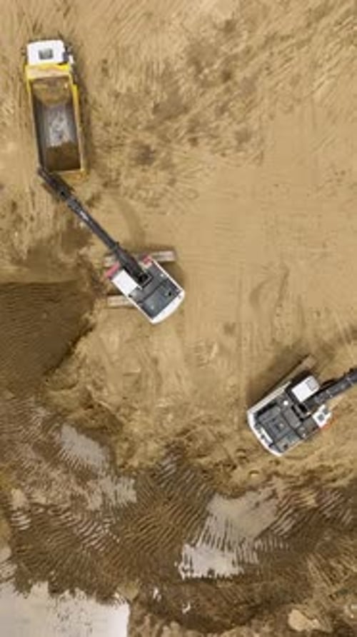 Heavy Machinery at Work: Excavators Loading Dump Trucks