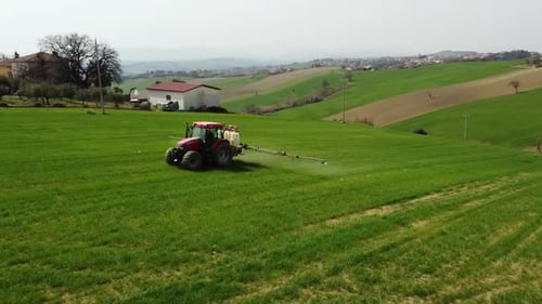 Aerial view of farming tractor spraying on field with sprayer, herbicides and pesticides insecticide