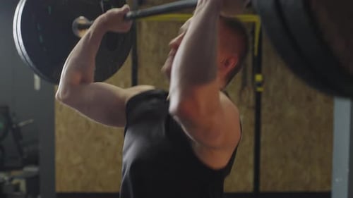 Athlete trains in gym with overhead lifting for strength and conditioning exercises