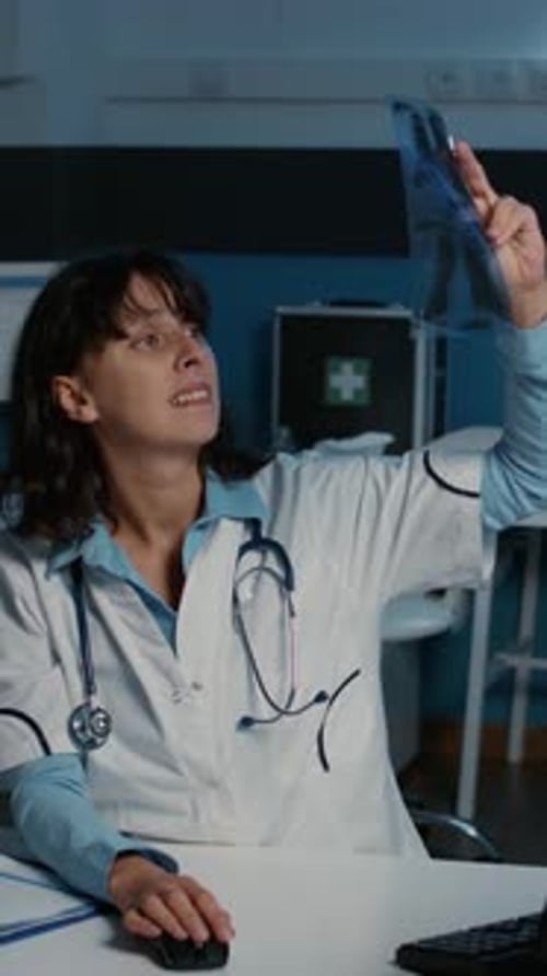 Female Doctor Examining X-Ray in Medical Office at Night