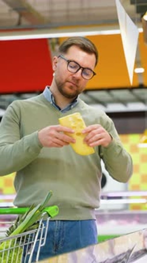Man Selecting Cheese in a Supermarket Dairy Section