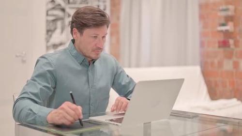 Man Works on Laptop and Graphic Tablet