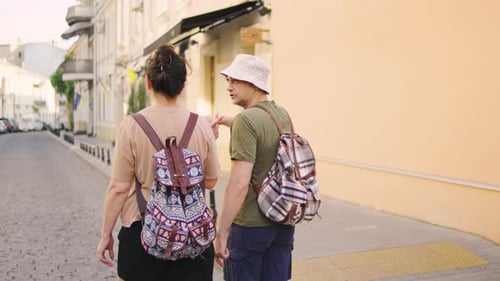 Two Aged Tourists Stand with Their Backs to the Camera Pointing at Landmarks and Discussing the