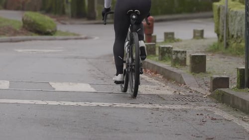 Rear view cyclist riding road bike on paved street