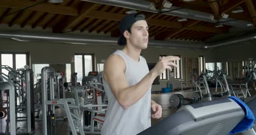 Futuristic portrait of a beautiful man in the gym on a treadmill uses a hologram to strengthen her