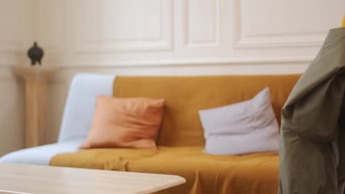 Woman Sets Down Olive Green Coat Indoors