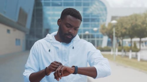 Individual Assesses Activity in City Environment Person Using Smartwatch Amid Modern Architecture