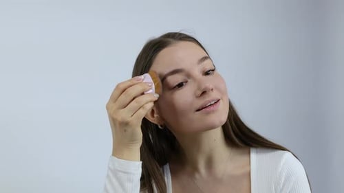 Young Woman Applying Makeup With Brush Indoors