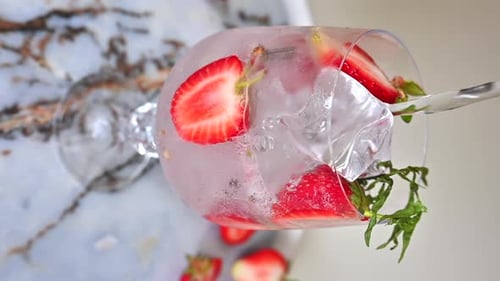 Water Pouring Into Glass with Strawberries and Ice