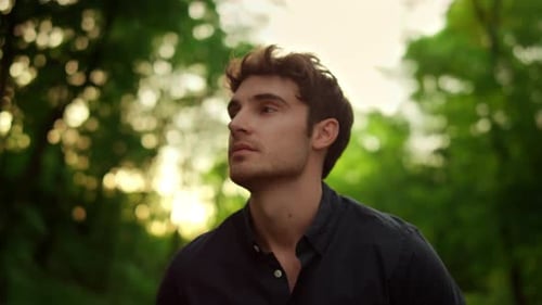 Relaxed man enjoying summer sunset walk on park road in slow motion