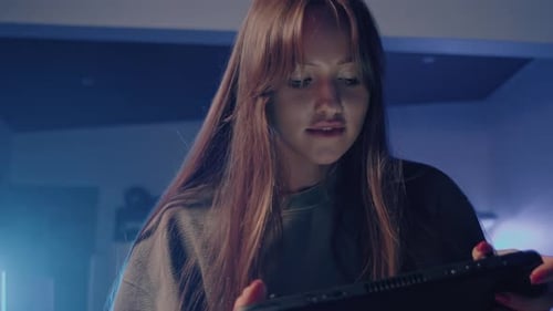 Young Adult Gaming on Portable Console at Night