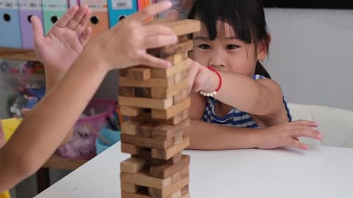 Cute Asian siblings having fun playing Jenga together.