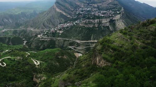 Sweeping View of Layered Mountainous Terrain with Lush Green Slopes and a Meandering Road
