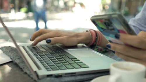 Businesswoman Working with Smartphone and Laptop Sitting in Cafe in City Alone
