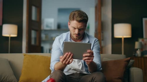 Man Browsing on Tablet While Sitting on Couch