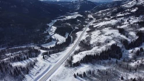 Winter road covered in snow with mountains in background