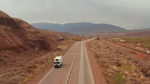 Aerial flying above along empty road trough sandstone rocks and desert flatlands, road trip
