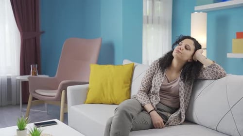 Woman Sits on Couch Thinking in Living Room