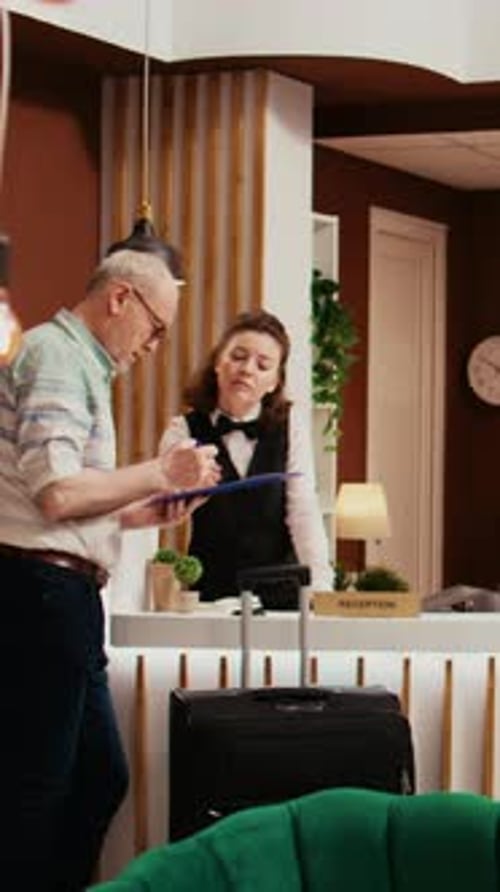 Man Signs Hotel Registration Form at Desk