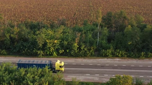 Aerial Shot of a Grain Truck Driving on the Road in Beautiful Countryside in the Summer Sunset Drone