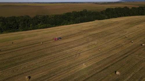 Aerial Panoramic View of the Tractor is Working on Wheat Field with Haystacks