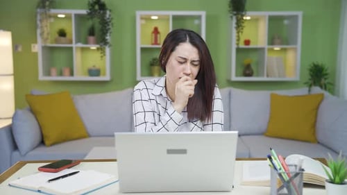 Woman Coughing at her Laptop at Home