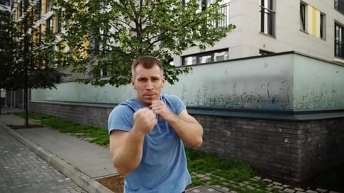 A Man Punches the Camera Slow Motion Green Trees on the Background of a Man in a Blue Tshirt